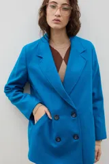 Blazer de lana con diseño bicolor, cuerpo en color negro y mangas en color crema. Presenta un corte holgado, cierre cruzado con doble botonadura y solapas amplias en contraste.