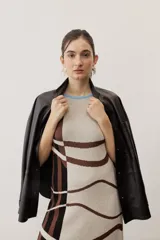 Vestido largo de punto con diseño geométrico y de ondas en color negro y crudo, sin mangas, con escote halter y detalle de flecos en el ruedo.