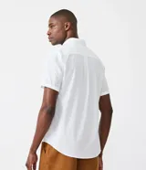 Camisa de hombre de manga corta color marrón, confeccionada en lino y algodón. Presenta cuello clásico, botonadura frontal, bolsillo en el pecho y mangas con botón para enrollar.