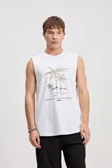 Musculosa oversize blanca de algodón, con sisas amplias y estampa frontal de inspiración tropical con palmeras y texto.