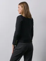 Chaqueta negra en tejido tweed de la marca Nanette. Tiene escote mao, abertura central y bolsillos delanteros. Los puños tienen apliques de botones perlados y la terminación es desflecada. Tiene forro interno.