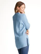 Blusa de lyocell color azul claro, con cuello camisero, escote en V y cierre frontal parcial con botones. Presenta mangas tres cuartos amplias y un corte holgado con aberturas laterales en el ruedo.