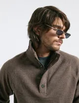 Sweater de punto color azul marino, con cuello alto, cierre frontal parcial y tapeta con botones. Presenta mangas raglán y puños y ruedo acanalados.