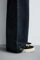 Zapatillas bajas de lona negra con cordones blancos y suela de goma blanca con textura.