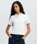 Blusa polo de algodón en color blanco, con mangas cortas, cuello y cierre frontal parcial con botones.