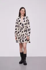 Vestido corto con estampado animal print en tonos beige, negro y azul. Tiene cuello mao, mangas largas con puños elásticos, cintura elastizada y falda con volantes.