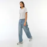Jean de corte baggy y tiro bajo, con diseño clásico de cinco bolsillos y cierre frontal con botón y cremallera. Presenta un lavado azul medio con acabado desgastado.