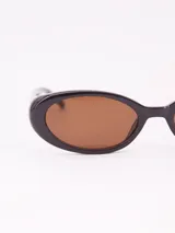 Lentes de sol con armazón ovalado de estilo retro en color negro y cristales oscuros.