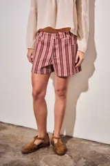 Short de tiro alto confeccionado en denim con diseño a rayas en tonos rosados, borravino y blancas. Cuenta con bolsillos delanteros y traseros, presillas para cinto y cierre frontal con botón metálico y cremallera.