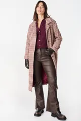 Pantalón de ecocuero color marrón, de corte recto con terminación ligeramente acampanada y tajos frontales en el ruedo. Cuenta con cierre y botón frontal, además de bolsillos laterales y traseros.