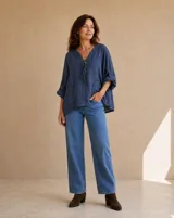 Blusa color azul jean con escote en V, cierre frontal con botones de madera y cordones ajustables, mangas largas con presilla y bolsillos delanteros con detalles desflecar.