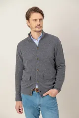 Sweater de lana lambswool color gris, con cuello alto, cierre frontal de botones y dos bolsillos delanteros tipo parche.