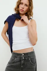 Jeans de tiro medio con cinco bolsillos, cintura doble a contraste y detalles de rotos. Cierre frontal con cremallera y botones metálicos.