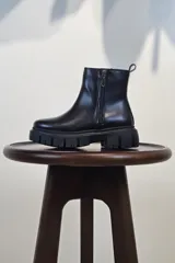 Bota de caña corta color marrón, con cierre lateral y suela track negra de goma con plataforma.