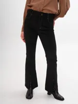 Pantalon de pana color marrón, de corte ajustado con costuras verticales frontales y tajos en el ruedo.