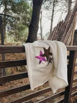 Saco tejido en lana color crudo, con corte recto, mangas largas y bolsillos frontales con apliques de estrellas de cuero en marrón, rosa y animal print.