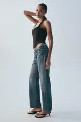 Jeans rectos de tiro medio en denim negro con efecto lavado. Presenta diseño de cinco bolsillos, trabillas para cinto y bajo con vuelta marcada. Cierre frontal con botones metálicos ocultos.