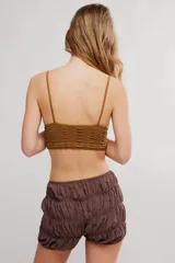 Bralette de encaje negro con copas triangulares, escote festoneado, tirantes finos regulables y banda inferior elastizada.