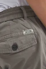 Bermuda cargo color gris oscuro, confeccionada en gabardina con efecto teñido. Presenta pretina elástica con cordón de ajuste, bolsillos laterales y bolsillos cargo con solapa en las piernas.