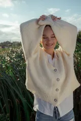 Cárdigan tejido en boucle color crudo, de corte holgado y mangas largas.