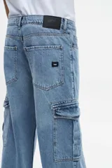 Pantalón de jean celeste con corte amplio, bolsillos laterales tipo cargo y tiro medio.