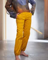 Pantalón babucha color beige de algodón, con corte a la cintura y piernas levemente amplias. Presenta textura de tablitas centrales y elásticos con broches inferiores que ajustan las piernas al tobillo.