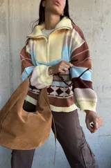 Sweater de tejido de punto con diseño a rayas horizontales y motivos geométricos, cuello alto con cierre frontal parcial, mangas largas abullonadas y puños acanalados.