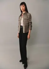 Camisa de estilo abrigo con diseño de cuadros, cuello camisero, cierre frontal con botones y dos bolsillos de parche en el pecho. Presenta manga larga con puños abotonados y un diseño de corte recto.