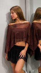 Top tipo capa de tul color bordó con diseño asimétrico y flores bordadas con lentejuelas. Presenta un corte holgado y escote tipo bote.