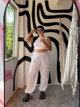 Pantalón palazzo de tiro alto, holgado, con estampado de hojas en tonos celeste claro y beige. Posee elástico en la cintura y lazos ajustables en los tobillos.