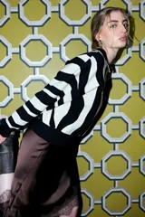 Sweater de punto con estampado de rayas onduladas en blanco y negro, cuello polo con botones y mangas largas.