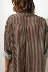 Vestido camisero midi de corte recto y holgado, con estampado de rayas verticales en tonos tierra, cuello camisero, cierre frontal de botones y mangas tres cuartos con puños vueltos.