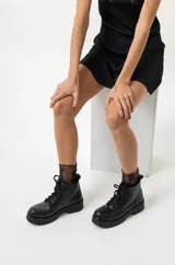 Borcegos de cuero negro con cordones, suela track y caña baja.