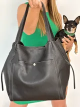 Bolso tote grande de cuero negro con costuras blancas y bolsillo externo con botón.
