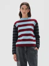 Polera de punto con diseño de rayas horizontales en tonos celeste y bordó en el cuerpo, y mangas a rayas en tonos gris y negro. Presenta cuello redondo y detalle de bordado en el pecho.