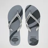 Ojotas Havaianas modelo Elegance Print, con base negra y gris con diseño de rayas diagonales. Las tiras son plateadas metálicas con textura en el borde.