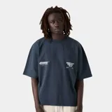 Camiseta azul marino de corte "boxy fit" con estampado blanco en la espalda que dice "Emecc" y texto adicional "DESIGN TEAM SELECTIONS / TABARCA BOATERS 2025 BUILDING A COMMUNITY THROUGH GRATITUDE".