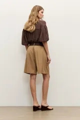 Short de lyocell color beige, de tiro alto y corte amplio, con pinzas delanteras y presillas para cinturón. Incluye un cinturón trenzado marrón oscuro con hebilla redonda forrada.
