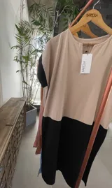 Vestido largo estilo túnica de algodón con diseño bicolor, cuerpo en tono tostado y parte inferior negra, de manga corta y cuello redondo.