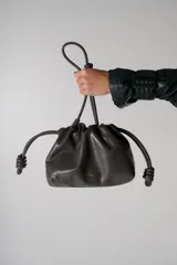Cartera tipo pouch color gris oscuro, con frunce superior y cierre con cordones del mismo material. Tiene logo de la marca estampado en dorado.