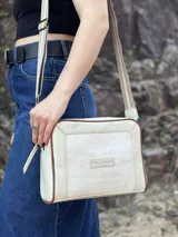 Bandolera rectangular color crema con textura símil cocodrilo, ribete marrón y correa larga de tela con rayas beige y marrón.