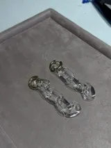 Aros colgantes de diseño maxi estilo cadena, compuestos por eslabones de vidrio transparente y argollas superiores en tono dorado.