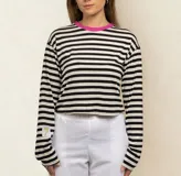 Remera corta de algodón a rayas horizontales blancas y negras, con cuello redondo en color fucsia y parche bordado en la manga izquierda.