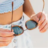 Lentes de sol Sunski modelo Bernina con armazón de carey en tonos caramelo y lentes polarizados color verde oscuro. Presentan un diseño de inspiración vintage con detalles metálicos en las bisagras y varillas.