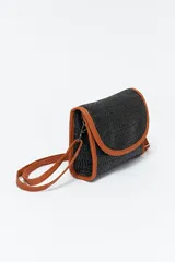 Cartera de mano tipo clutch, tejida en fibra sintética color negro con borde y correa de muñeca color marrón.