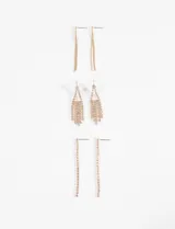 Set de tres pares de caravanas colgantes en tono dorado con incrustaciones de strass. Incluye un par de cadenas finas, un par con diseño triangular y flecos, y un par de tiras largas de strass.