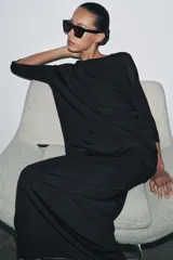 Prenda superior negra de punto liso, con cuello redondo y mangas tres cuartos. Presenta aberturas laterales en el bajo.