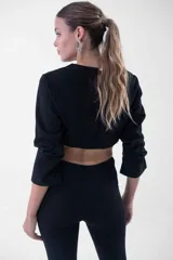 Top negro corto con mangas largas, cuello redondo y detalle de flecos de strass colgantes en el ruedo.