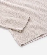 Remera de manga larga estilo Henley, confeccionada en tejido texturizado color beige, con cuello redondo y cierre frontal parcial de botones.