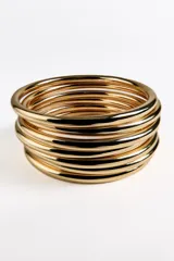 Pack de pulseras rígidas doradas, compuestas por múltiples aros delgados superpuestos, creando un efecto de brazalete ancho y texturizado.